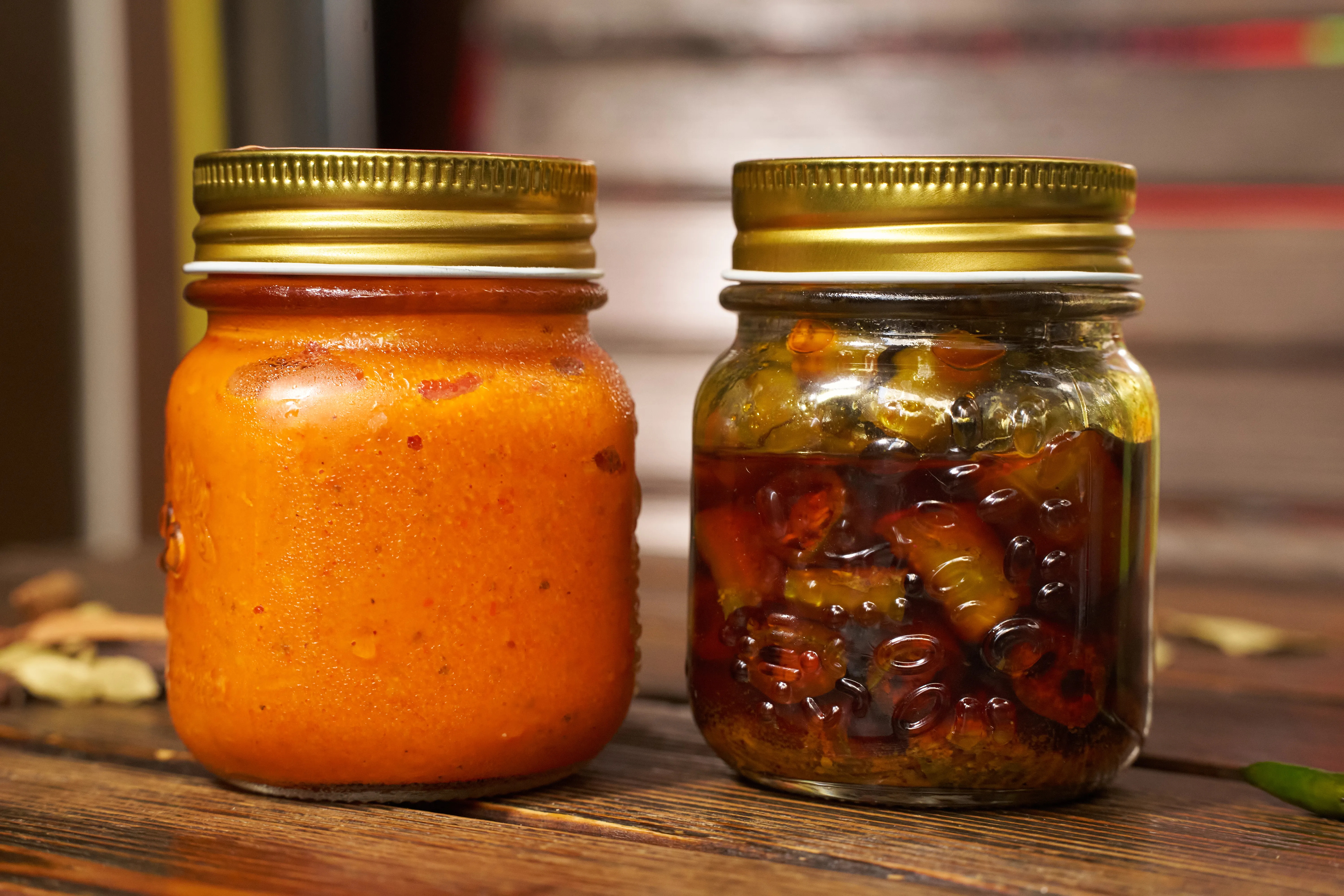 Two Mason jars of Mama Gomes condiments: red chilli paste and green chilli pickle in oil